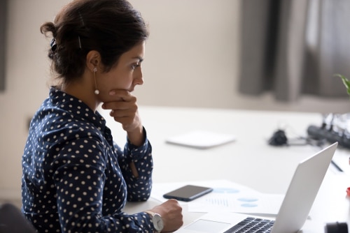 Businesswoman sitting at a desk looking at a laptop