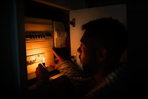 Man With Lighter In Total Darkness Investigating Fuse Box