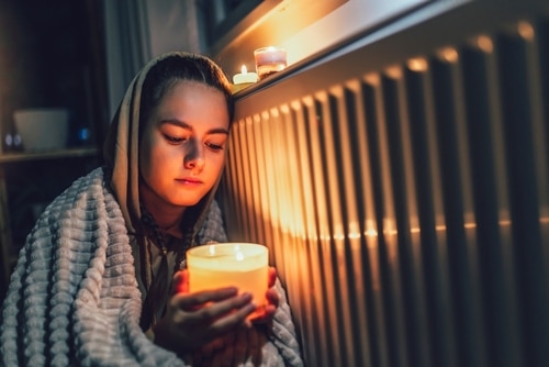 Child sitting next to a heater with candle during a power outage