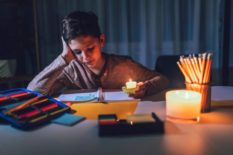 Little boy doing homework by candle light during a Power Outage