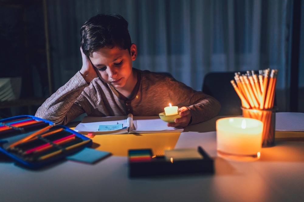 Little boy doing homework by candle light during a Power Outage