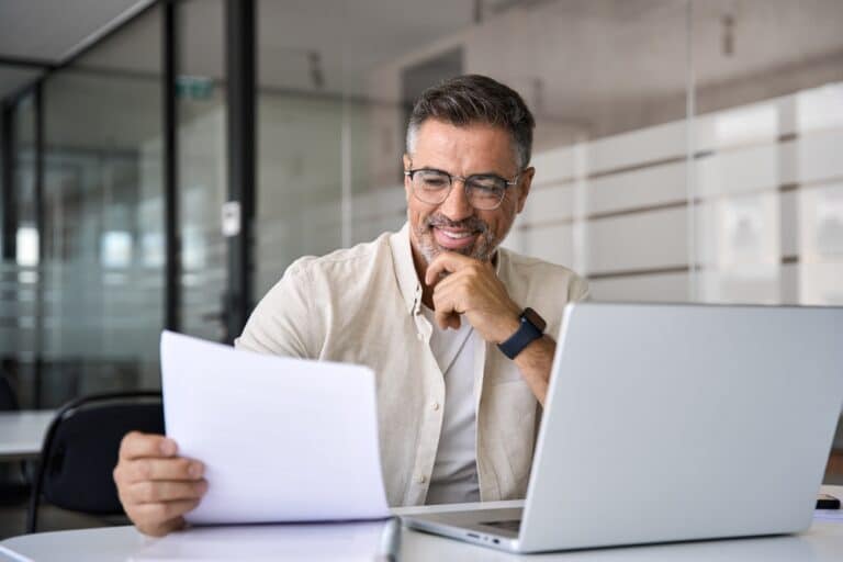 Businessman with laptop looking at paperwork