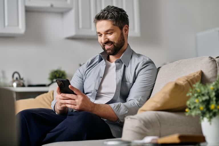 Man sitting on a couch looking at his cell phone