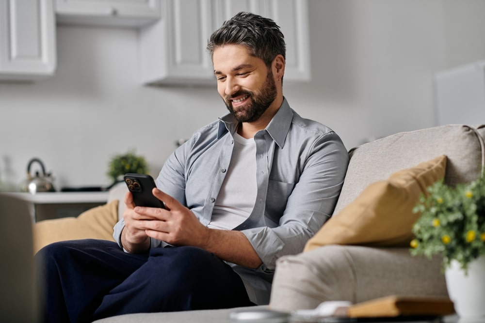 Man sitting on a couch looking at his cell phone